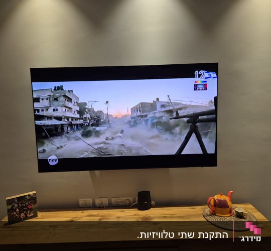 טלוויזיה מותקנת על קיר מעל מזנון עץ בסלון